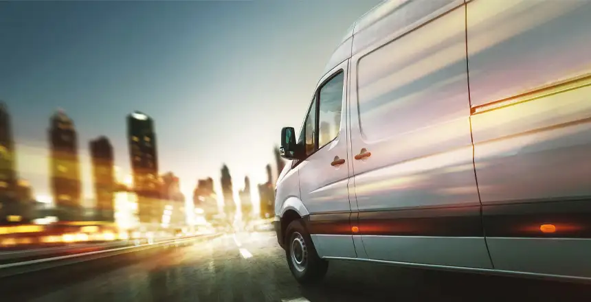 Transporter vor Skyline einer Stadt in der Dämmerung