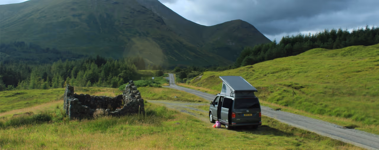 Campervan am Wegrand auf der Isle of Mull mit grüner Wiese und Berg im Hintergrund